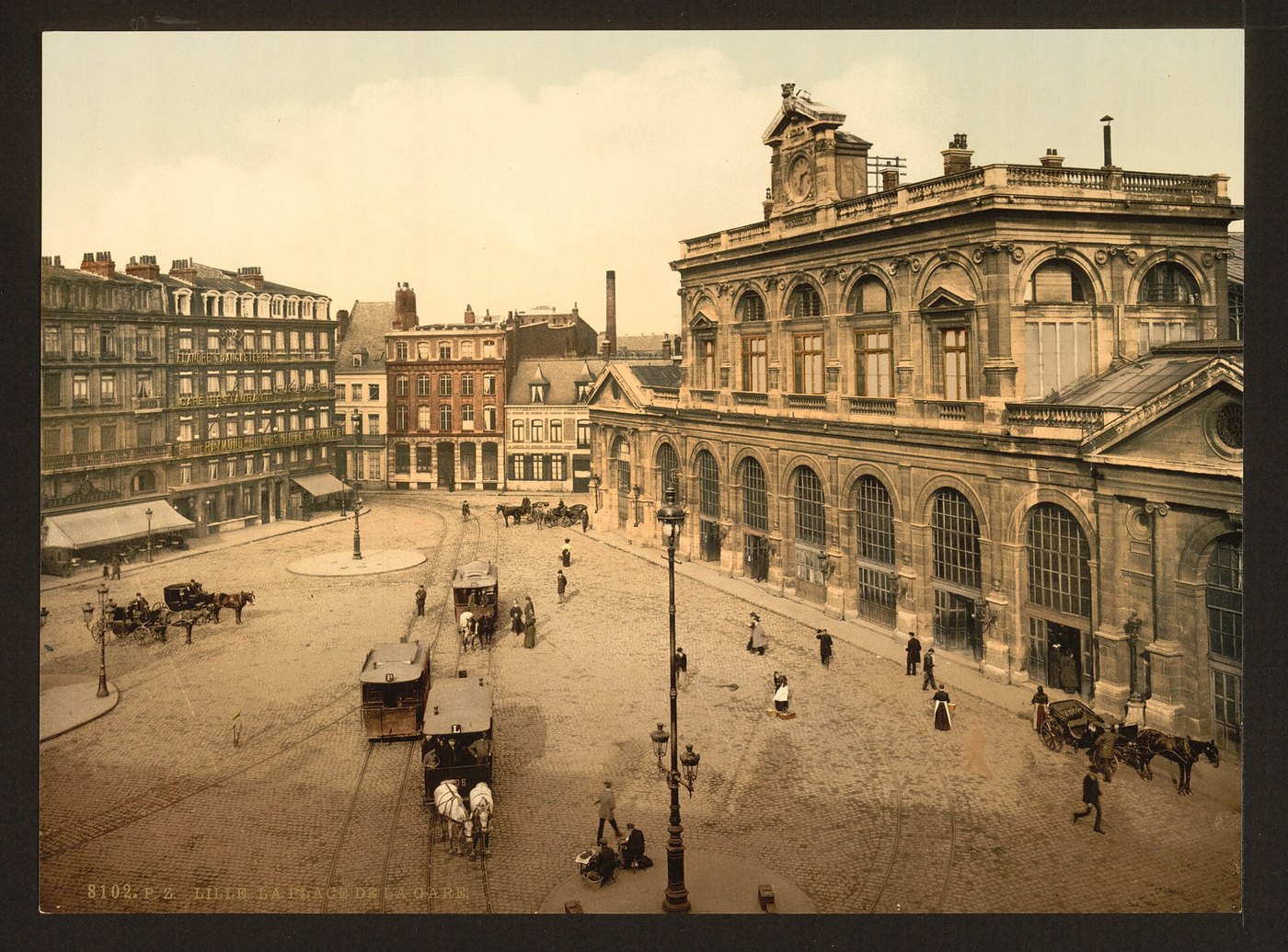 Place de la Gare à Lille, entre 1890 et 1900. Au premier plan, deux tramways à impériale tirés chacun par un attelage de deux chevaux, sur les rails encore visibles dans le pavé.